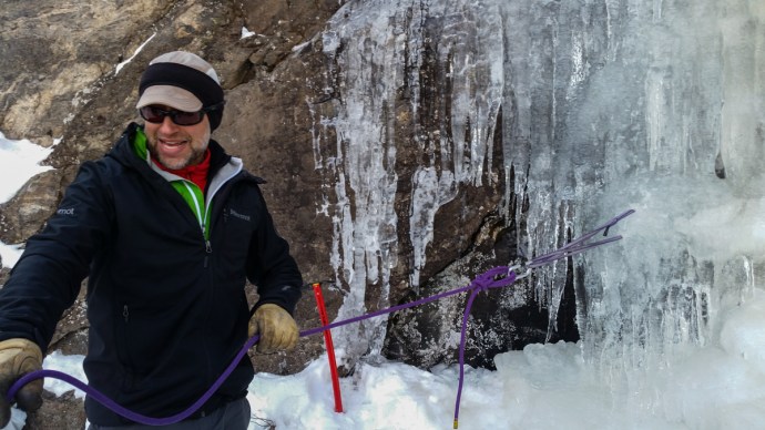 Bob demonstrating how to use ice screws to create an anchor in ice