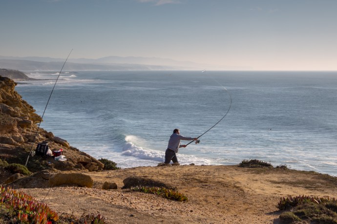 Fisherman casting from atop the cliffs above Ribeira d'Ilhas .  He would send his bait flying about 100 yards into the ocean below!